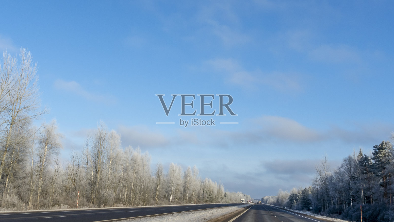 乡村公路穿越冬日田园风光。黑色的干净的沥青。穿过白雪覆盖的田野的冬季道路。照片摄影图片