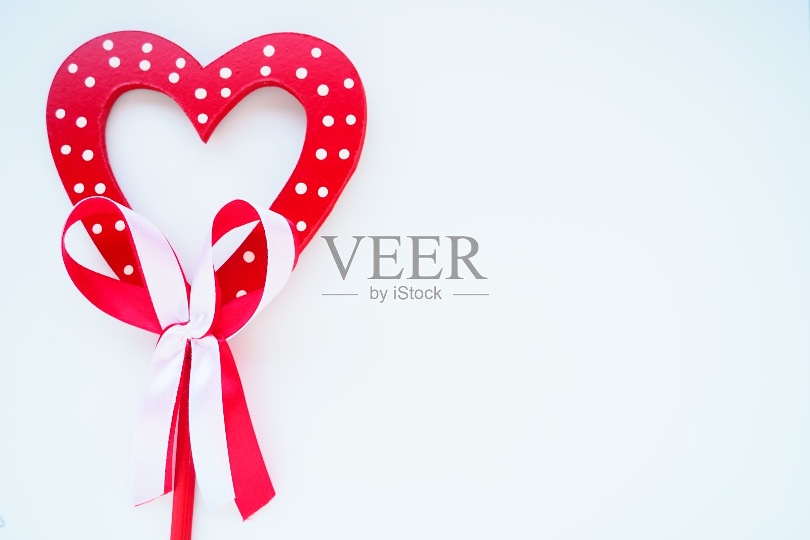 情人节的概念。红色木制心型,上面有白点和丝带蝴蝶结。白色背景。作为装饰的漂亮的弓。爱和关系。识别或祝贺照片摄影图片