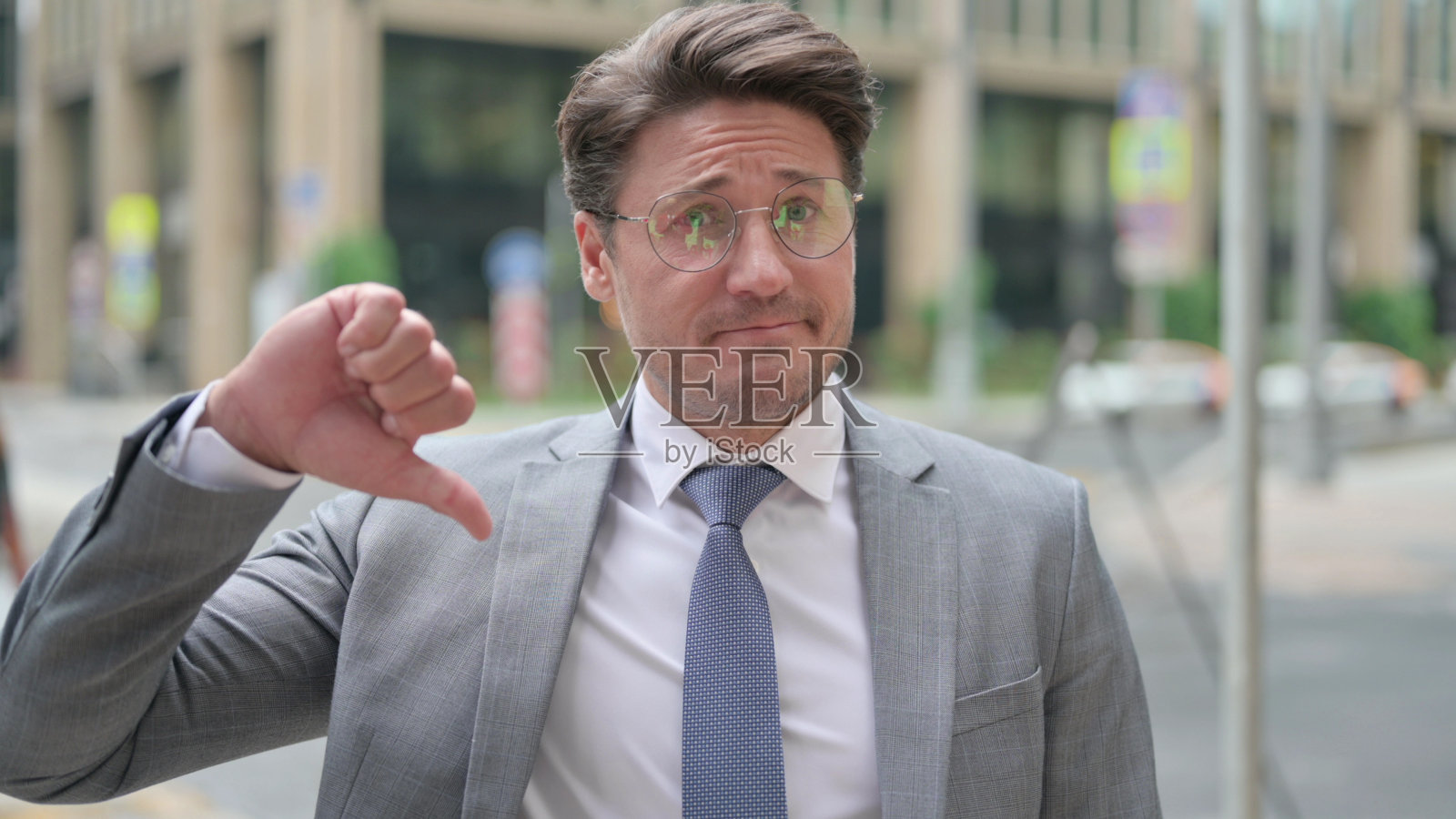 中年男子在户外用拇指向下照片摄影图片