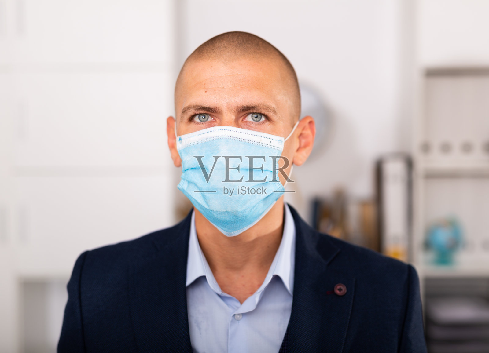 戴着医用口罩的经理站在现代办公室里照片摄影图片