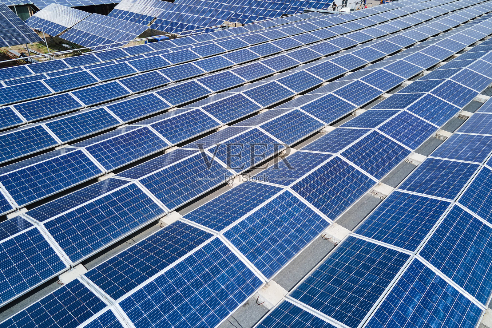 太阳能发电厂鸟瞰图,蓝色光伏板安装在工业建筑屋顶上,产生绿色生态电力。生产可持续能源的理念。照片摄影图片