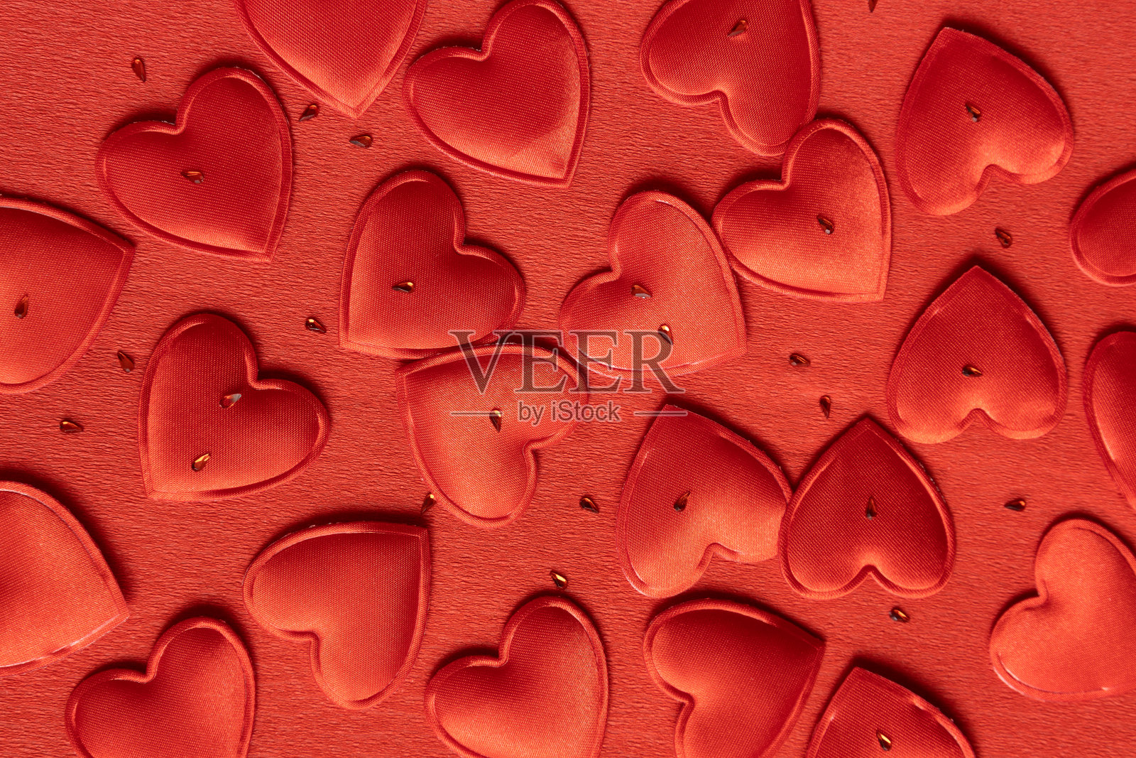 红色包装纸上装饰性红色心形和莱茵石的俯视图作为背景照片摄影图片