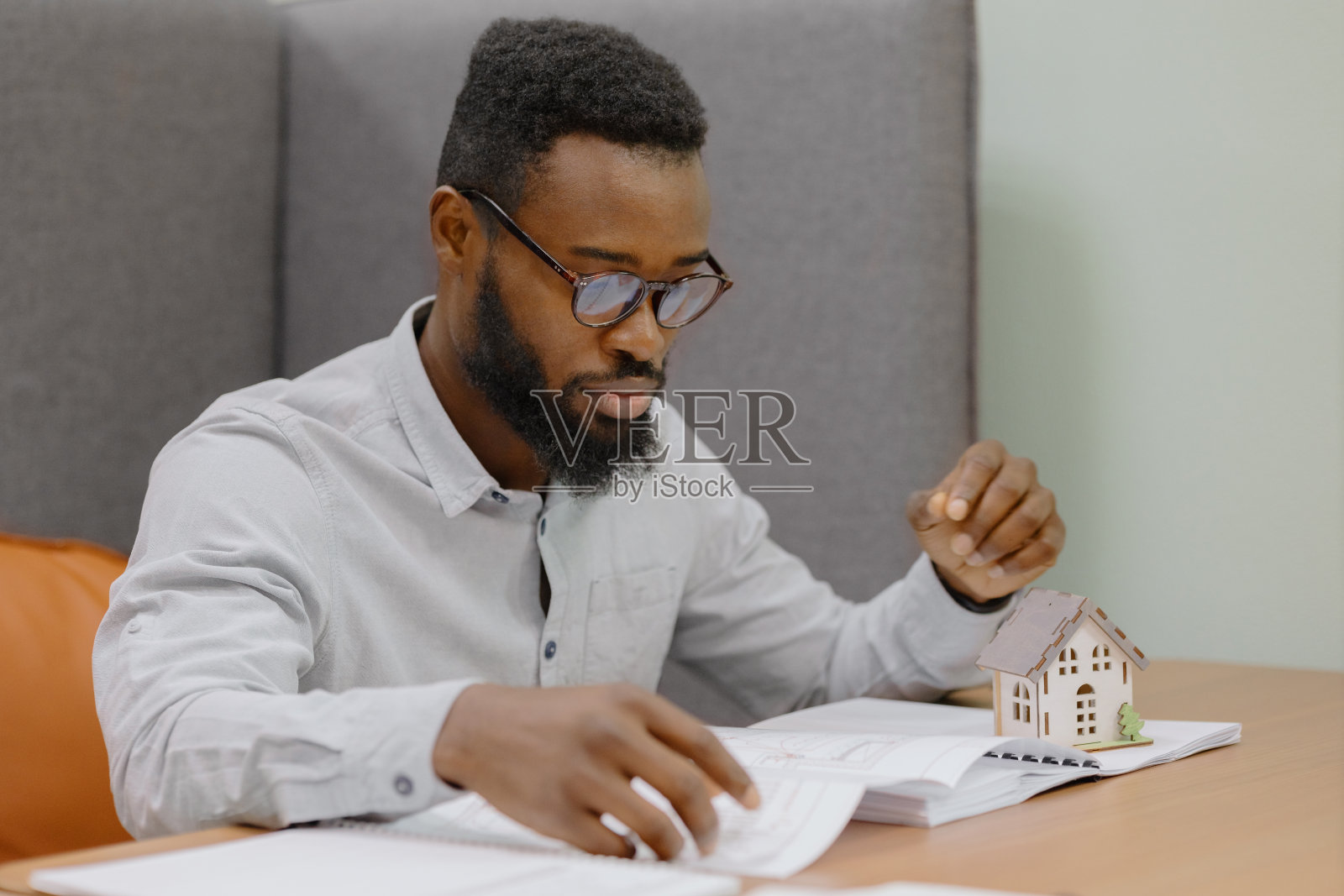 一位非裔美国男性建筑师、工程师或设计师在一个住宅建筑项目的办公室工作。一位非裔美国人手里拿着一幅微型画照片摄影图片