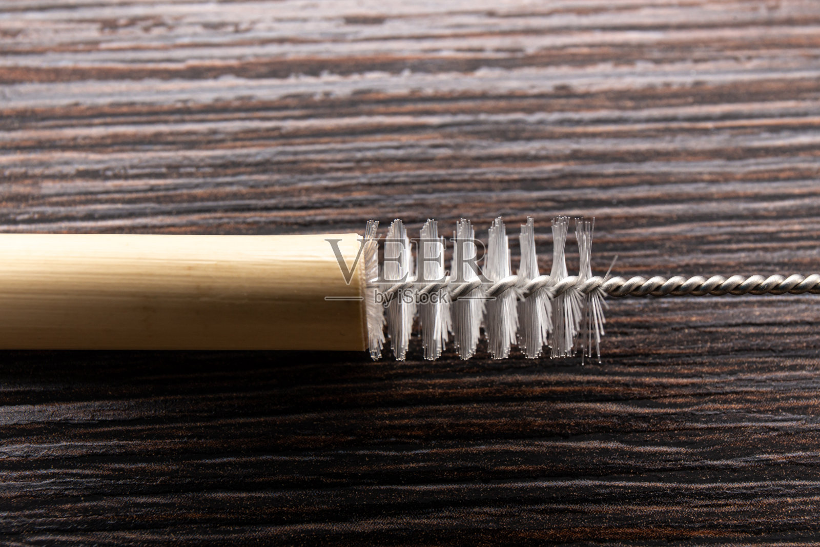 近距离观看使用吸管清洁刷清洁可重复使用的竹吸管,在室内。照片摄影图片