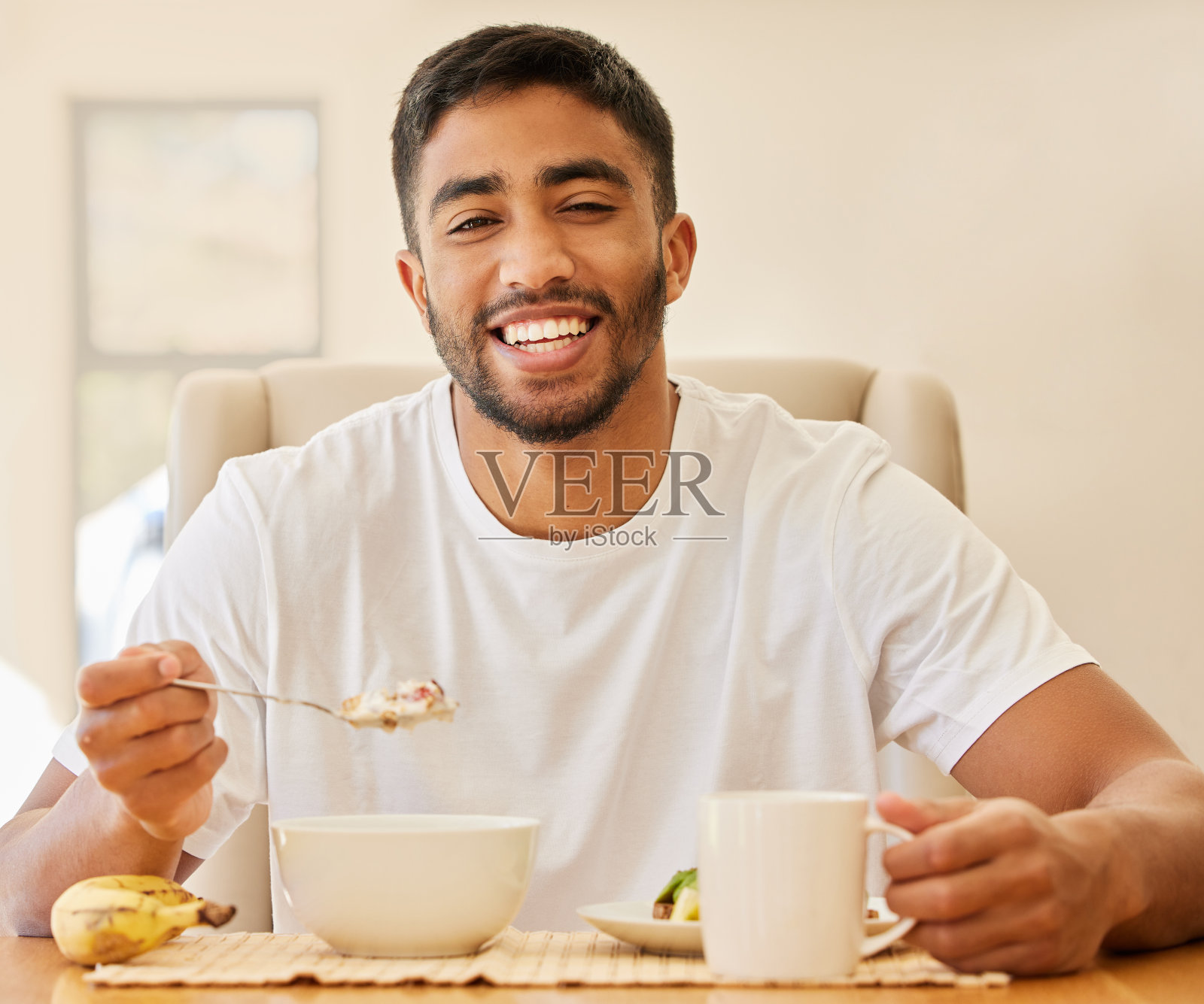 一个英俊的年轻人独自坐在家里吃早餐照片摄影图片