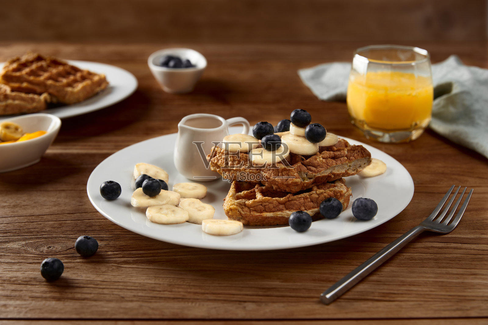 质朴的木桌上放着比利时燕麦华夫饼,上面点缀着香蕉和蓝莓照片摄影图片
