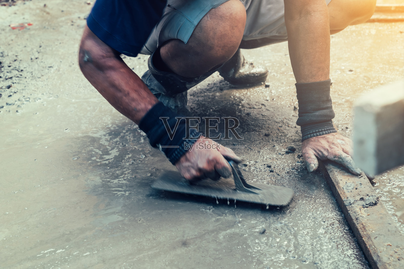 运动模糊泥瓦匠在家里用阳光建造平层水泥。照片摄影图片