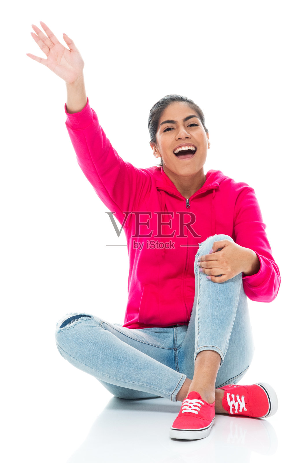 z一代年轻女性穿着牛仔裤坐在白色背景前面的地板上照片摄影图片