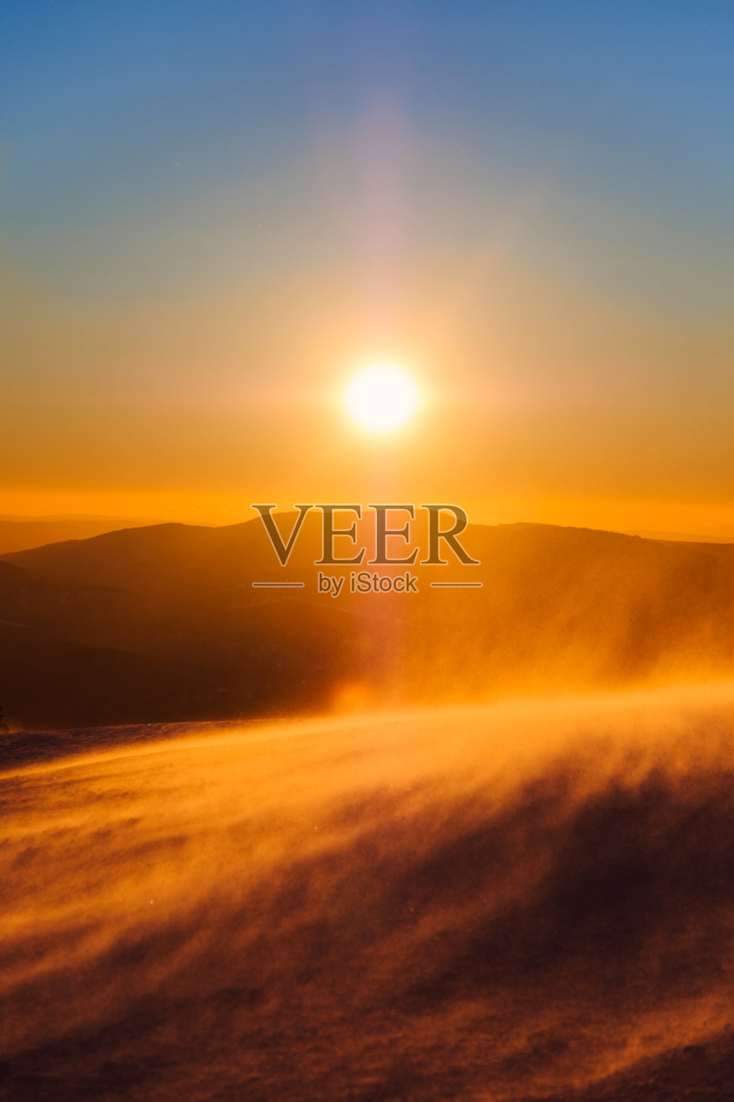 日落在山和雪中呈现出橙色和蓝色的色调照片摄影图片