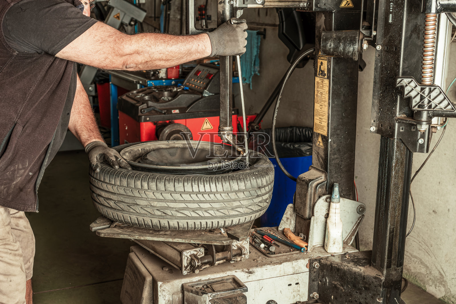 机械师用电动工具从车轮上取下导线照片摄影图片