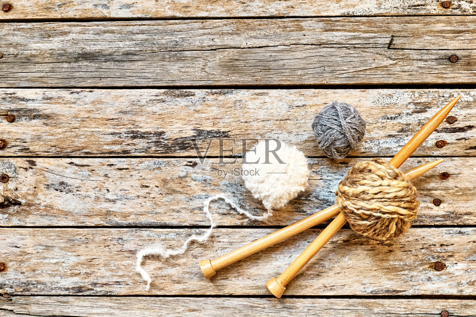 桌子上放着一团一团的毛线和木制编织针。爱好工艺背景与文字空间。针织概念,针线活。照片摄影图片