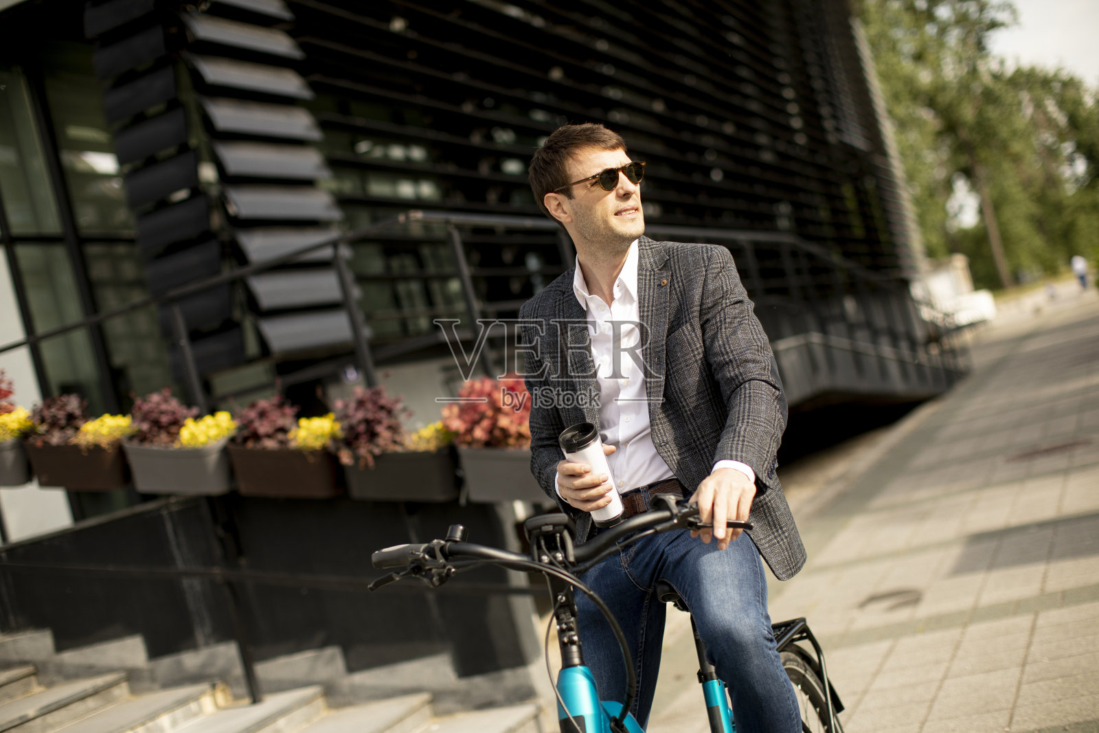 年轻的商人骑着电动车,端着外卖咖啡杯照片摄影图片