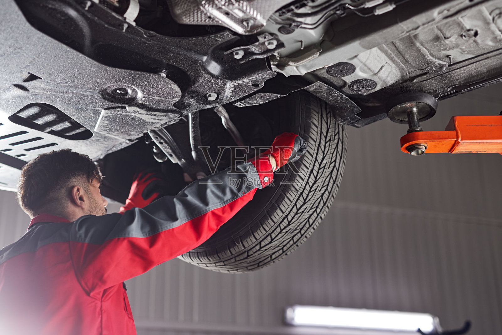 修理汽车车轮的男性技工照片摄影图片