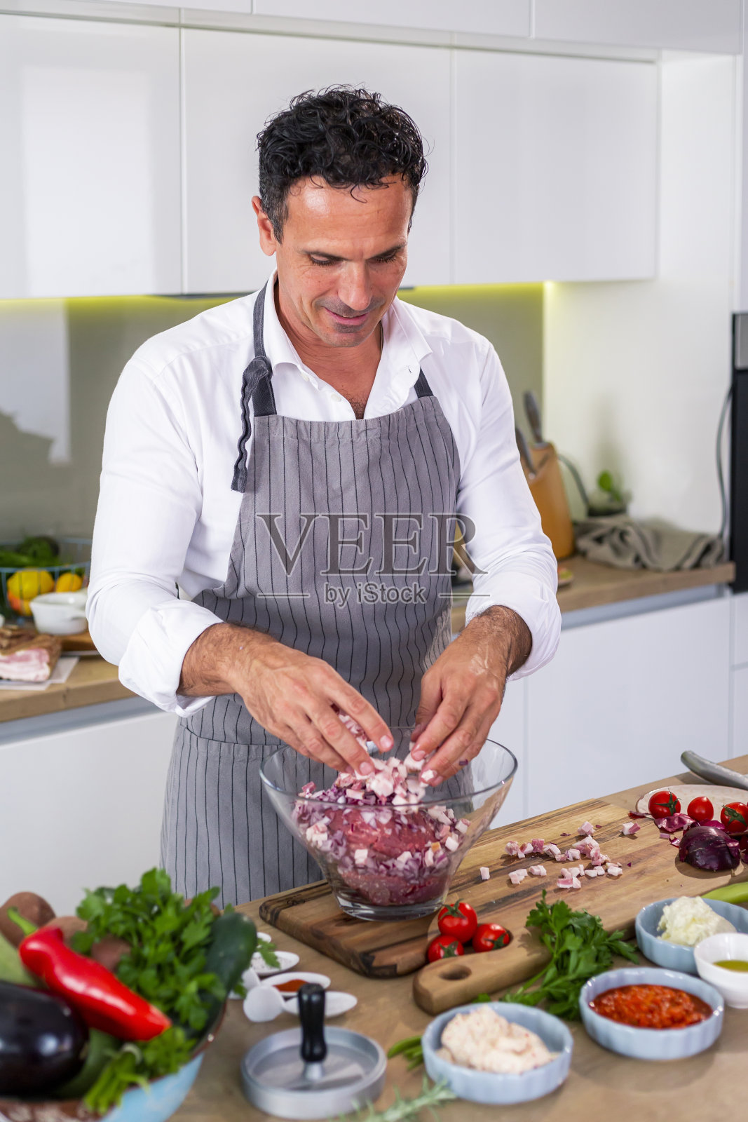 厨师把培根、肉和洋葱放入碗中。照片摄影图片