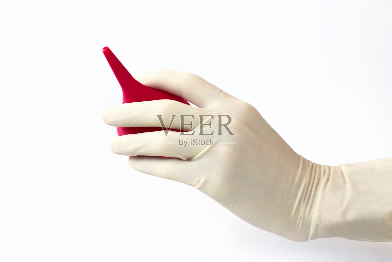 戴着医用手套,手上有一个带软尖的粉色注射器。灌肠能容纳一个女人。白色背景。医疗灌肠。医疗程序和程序。照片摄影图片