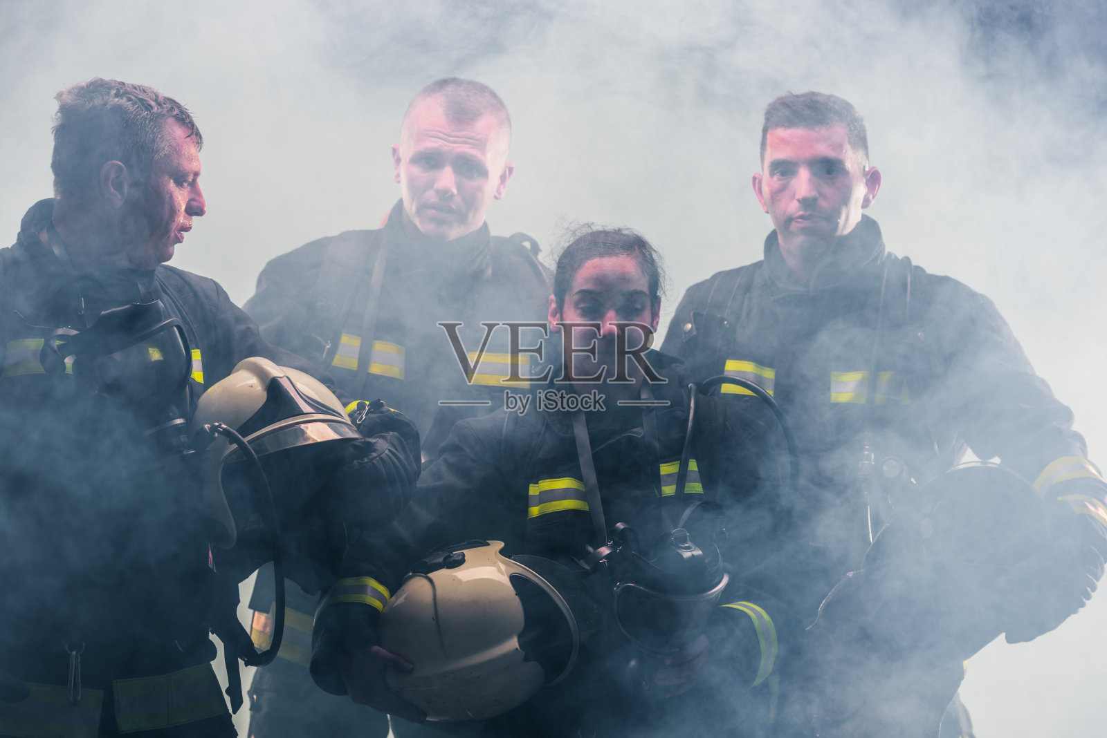 一队消防队员站在消防局内部灭火器的烟雾中间照片摄影图片