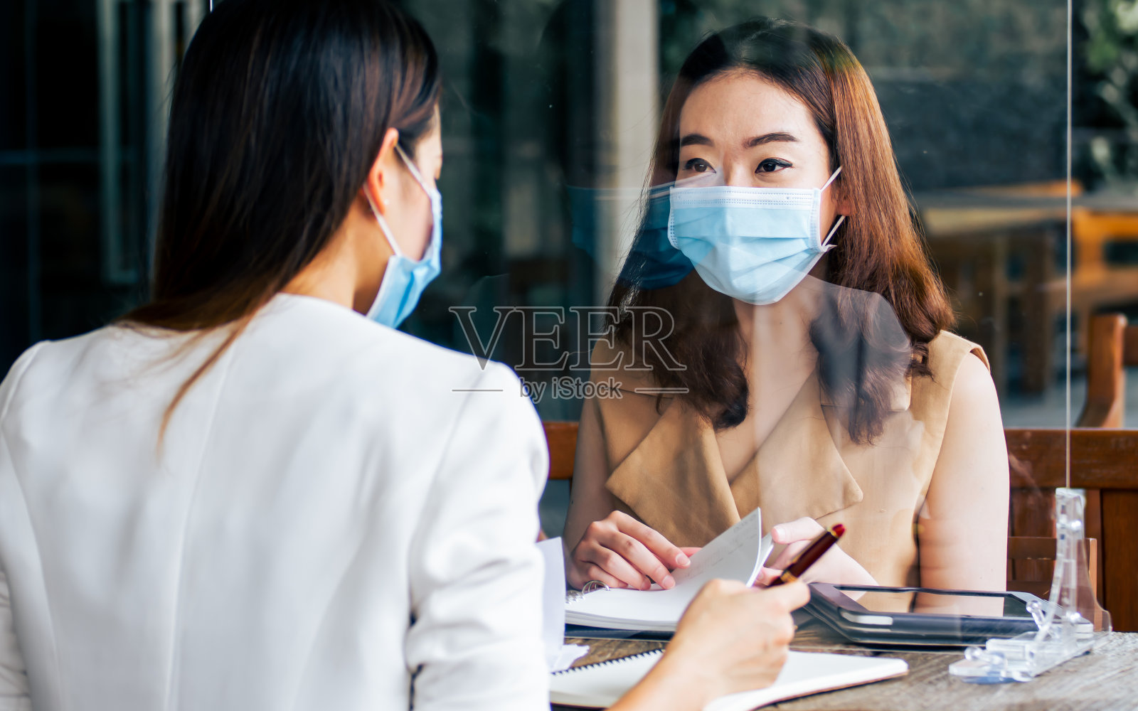 亚洲美女商人,在咖啡厅工作,聊天,与同事或同事见面时,戴着口罩,保持社交距离,保护病毒。新常态与经营理念。照片摄影图片