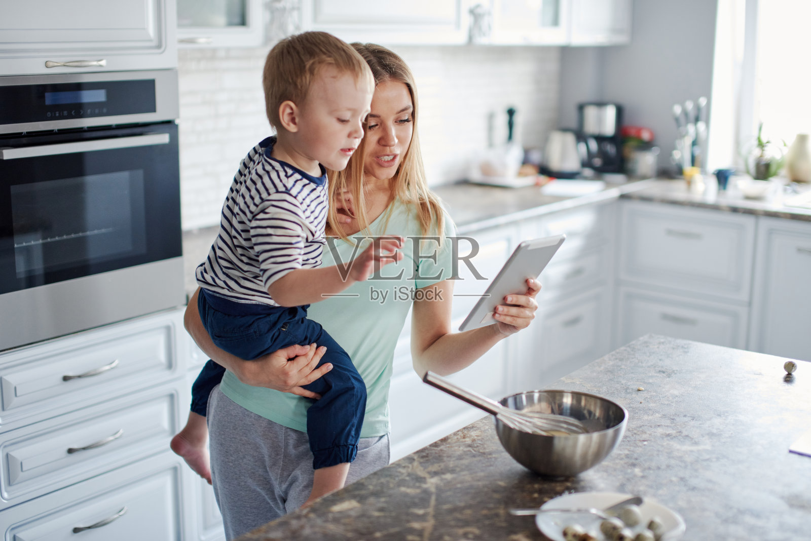 忙碌的妈妈手里拿着平板和儿子照片摄影图片