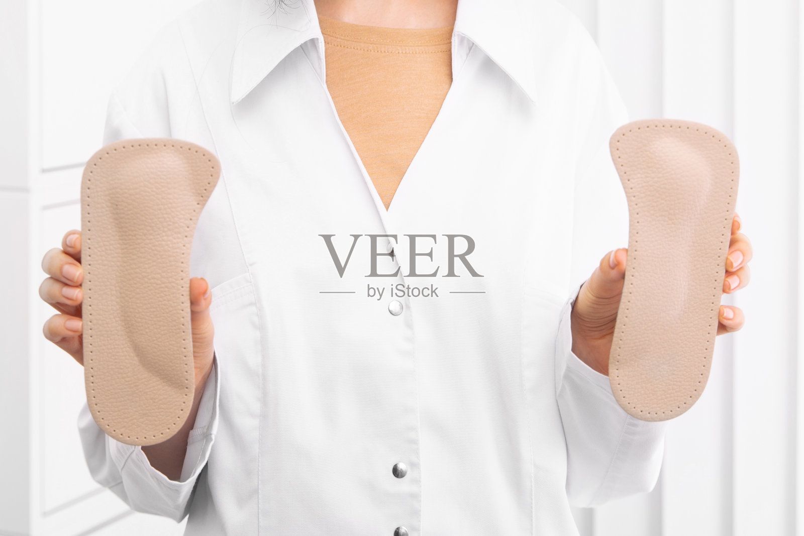 医生手里拿着矫形鞋垫。骨科医生测试医疗设备。矫形鞋垫上的白色。足部护理。扁平足的修正。预防扁平足和足部疾病照片摄影图片