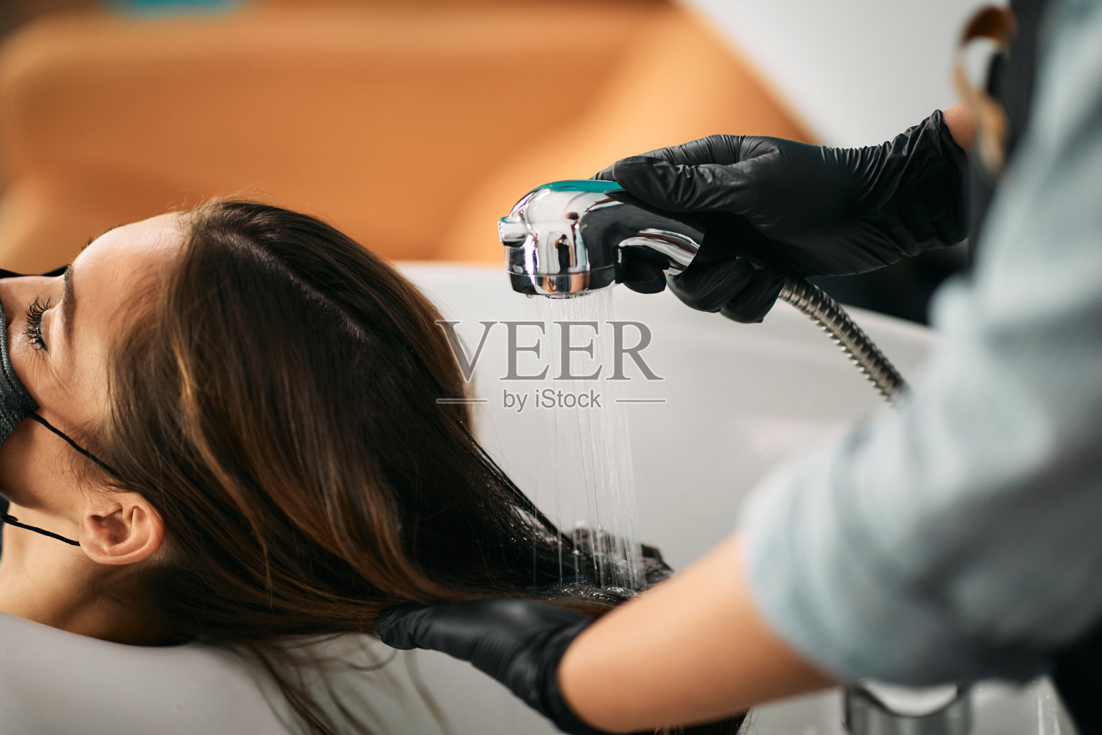 美发师洗头发的一个女人在沙龙的特写。照片摄影图片