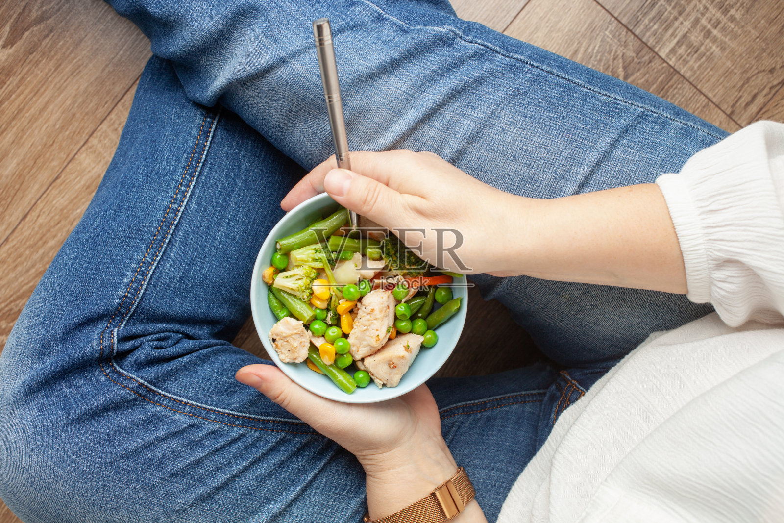 这个女人端着一碗午餐——鸡肉和蔬菜。俯视图照片摄影图片