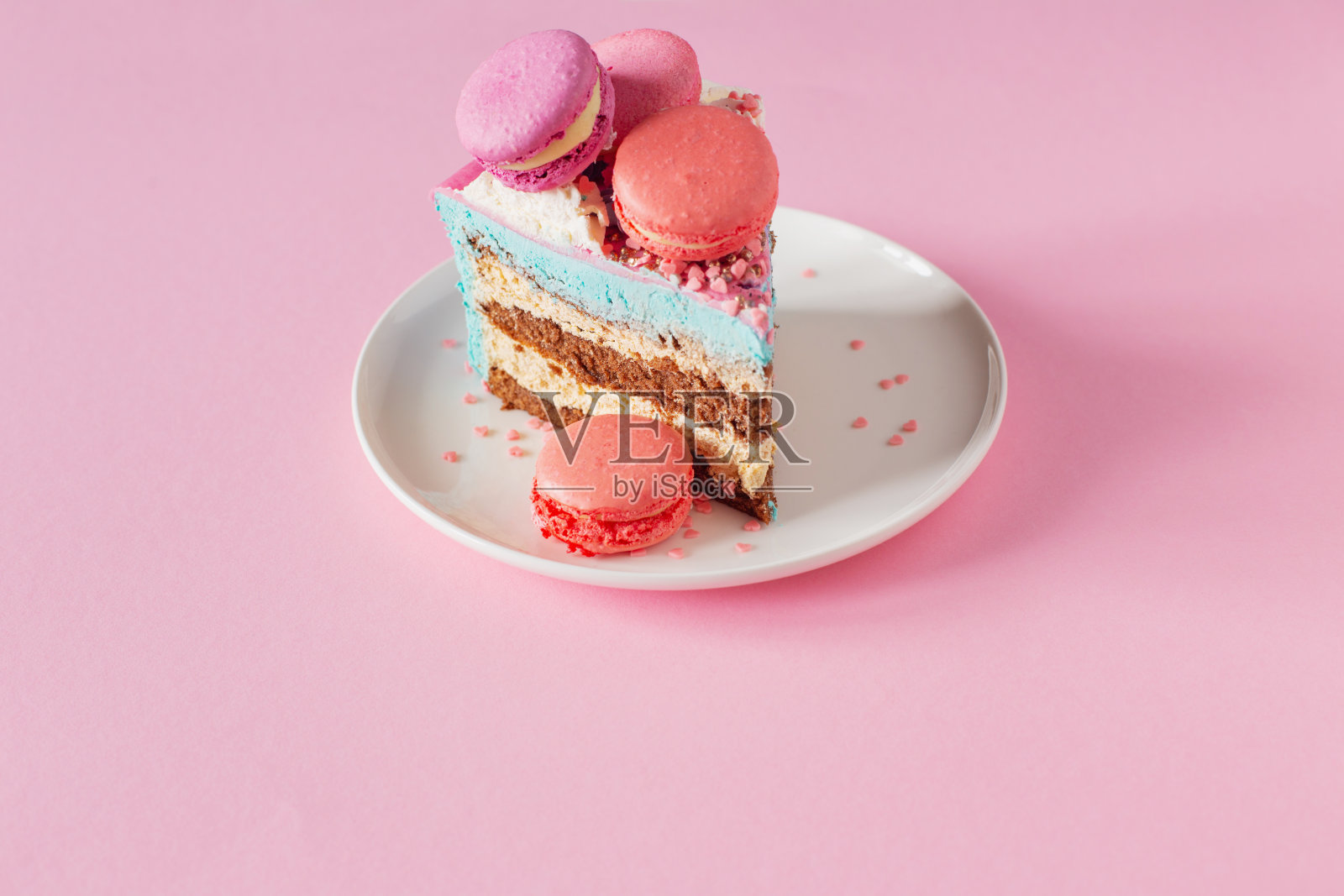 粉色和蓝色装饰的蛋糕,白色的盘子在粉红色的背景上照片摄影图片