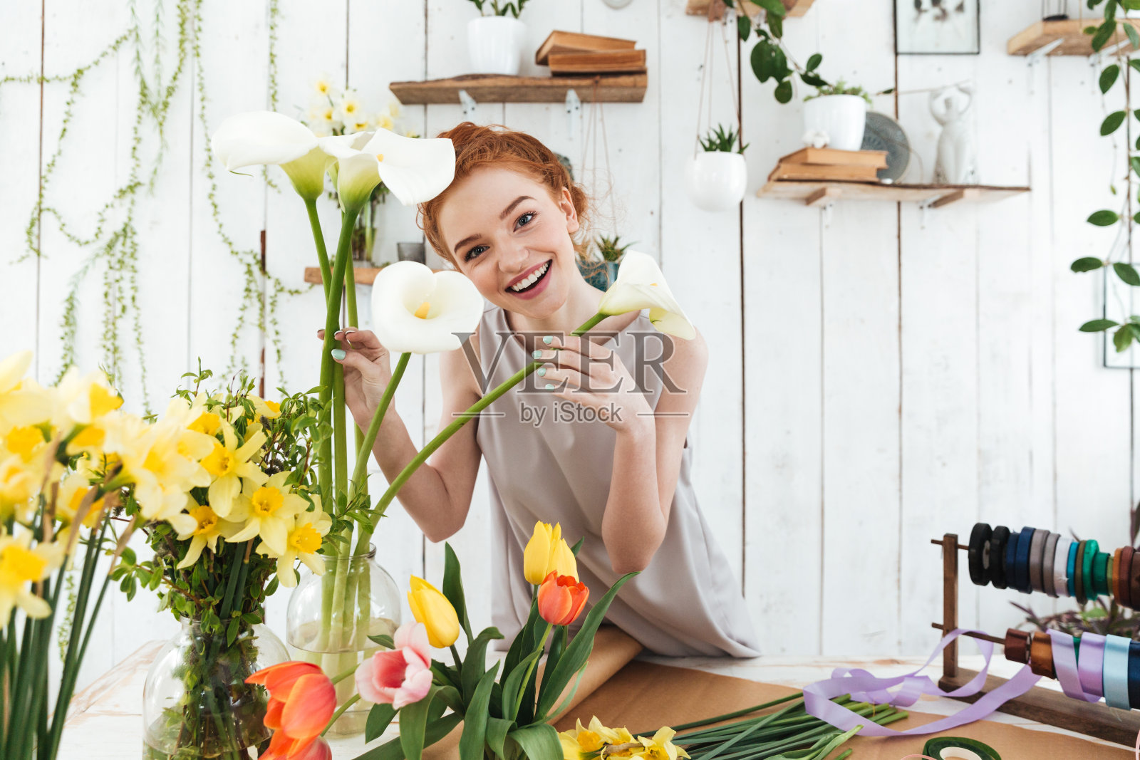 快乐的女士看着相机,而持有白色马蹄莲照片摄影图片