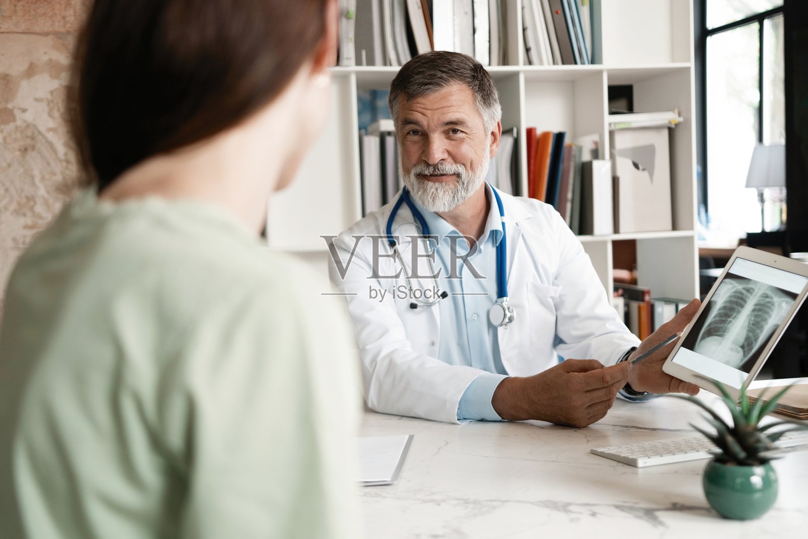 开朗成熟的医生在办公室听病人解释她的痛苦。照片摄影图片