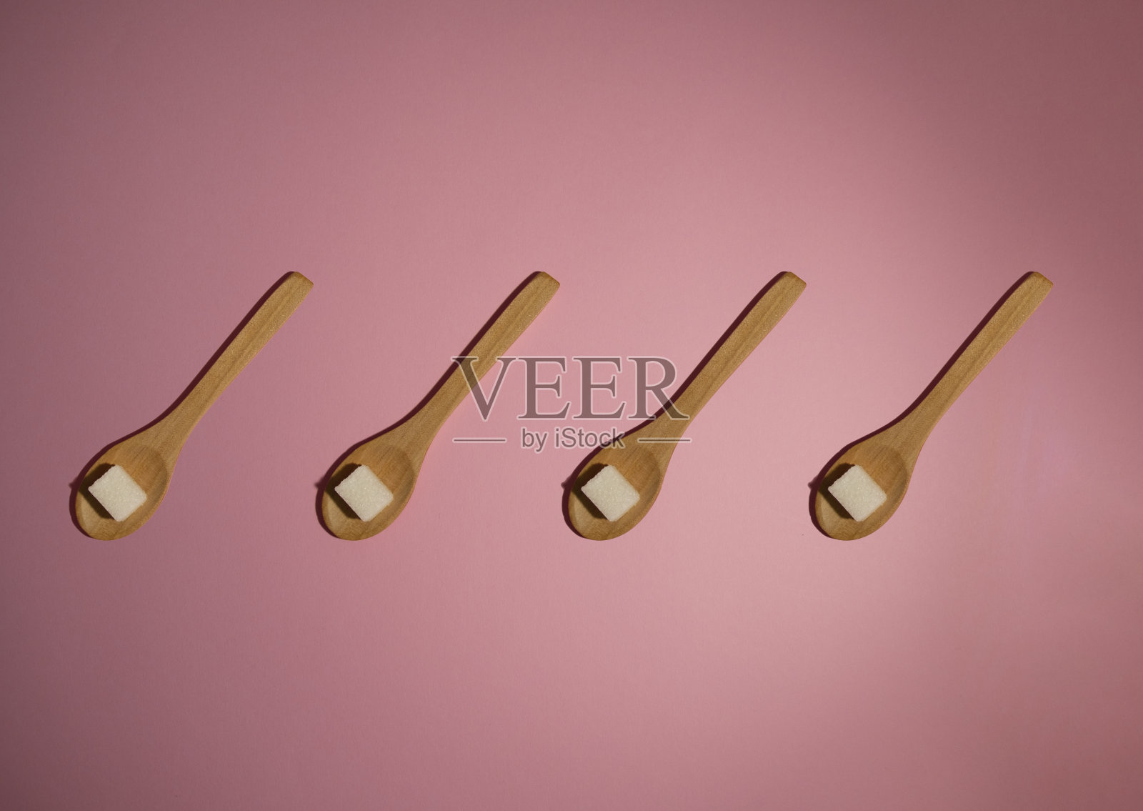 粉色背景下的木勺糖果照片摄影图片