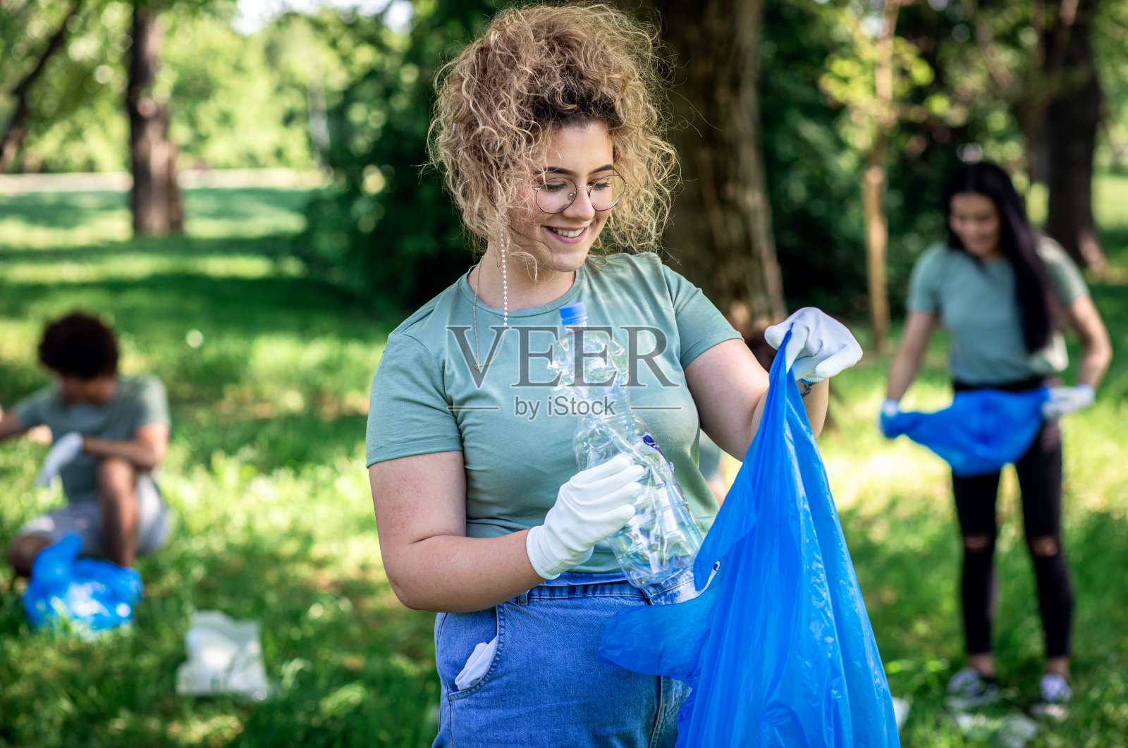 和朋友们一起用垃圾袋清理城市公园的女人的肖像。照片摄影图片