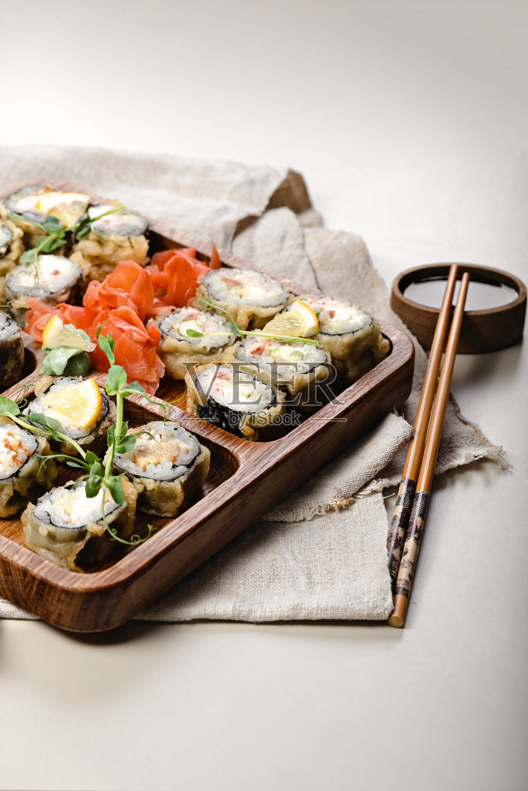 热的寿司卷。木器上有虾的烤面包卷。竹筷和酱油。副本的空间。垂直拍摄照片摄影图片