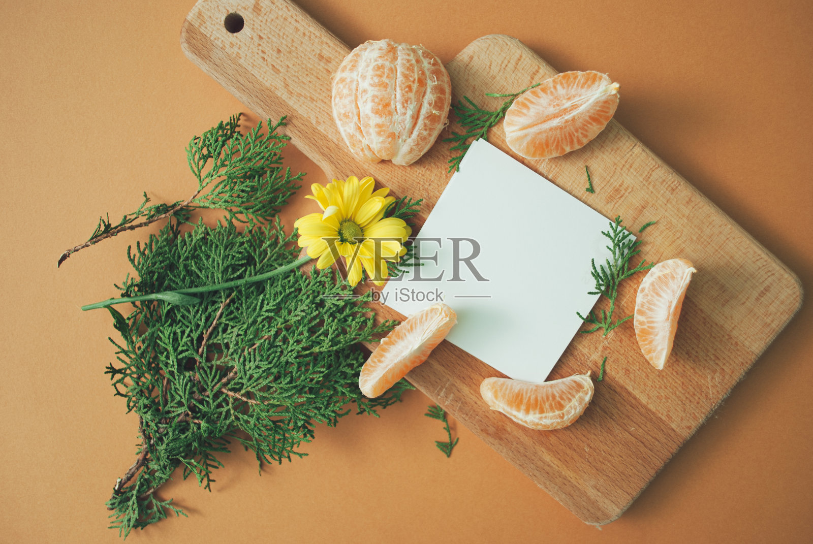 柑橘与天然的常青荆棘,黄色的花在砧板和复制空间在橙色的背景。前视图。照片摄影图片