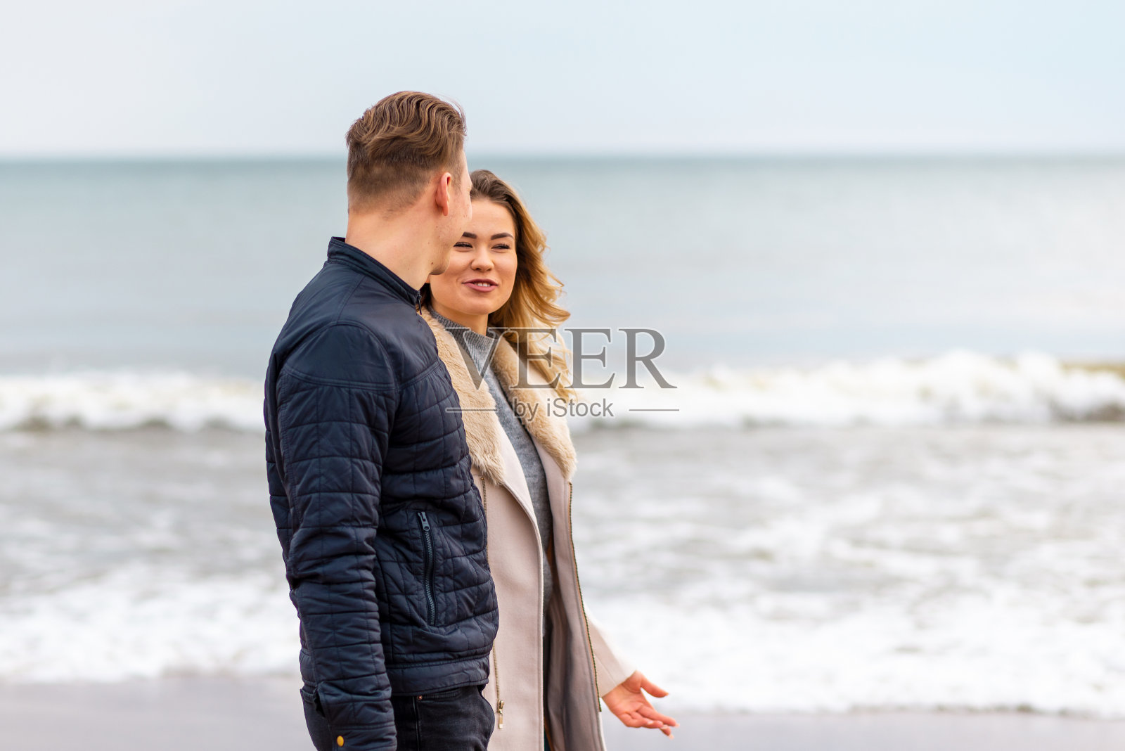 迷人的年轻夫妇沿着沙滩散步,在一个春天浪漫的假期,户外。照片摄影图片