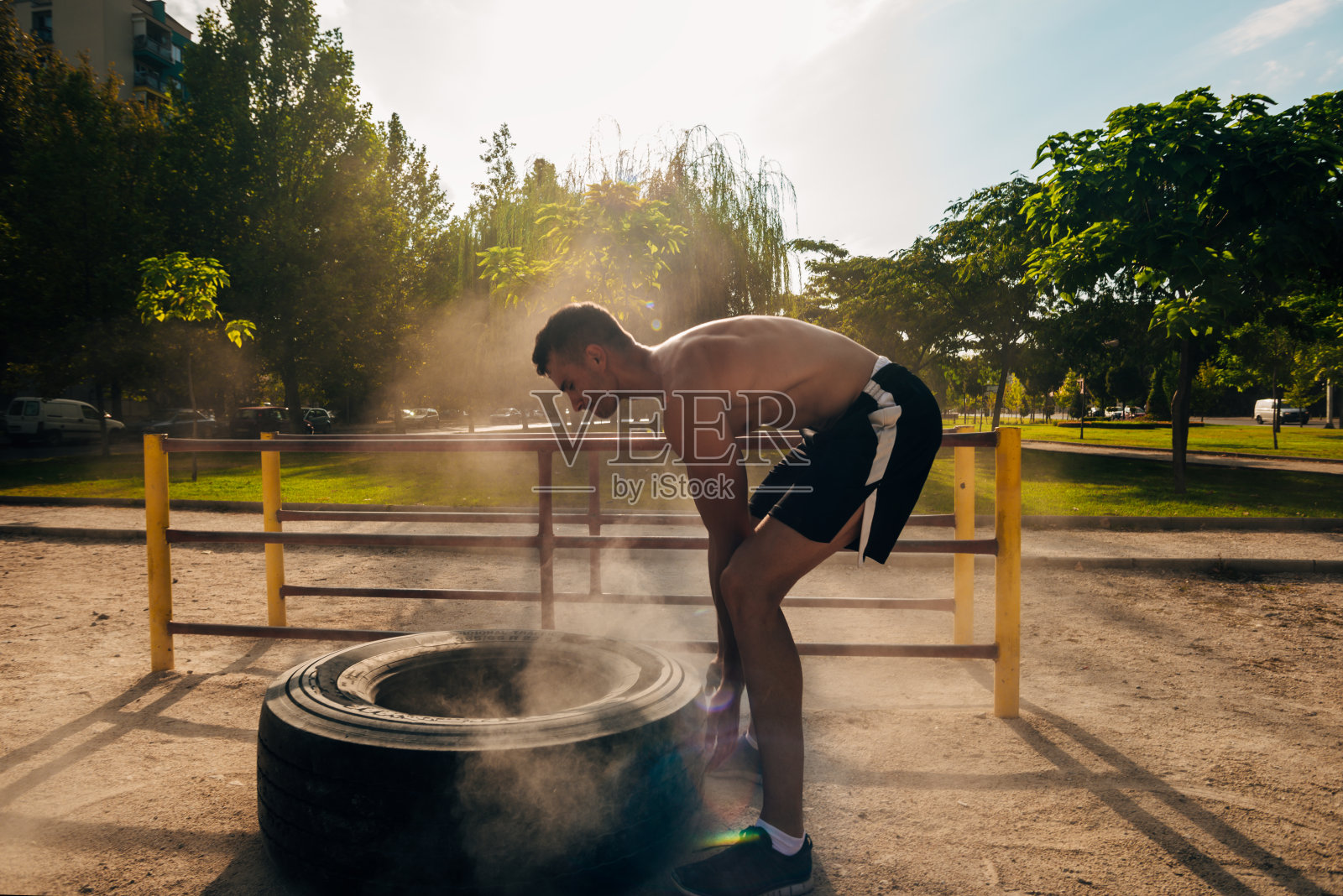 肌肉发达的运动员在街头健身房用大轮胎训练照片摄影图片