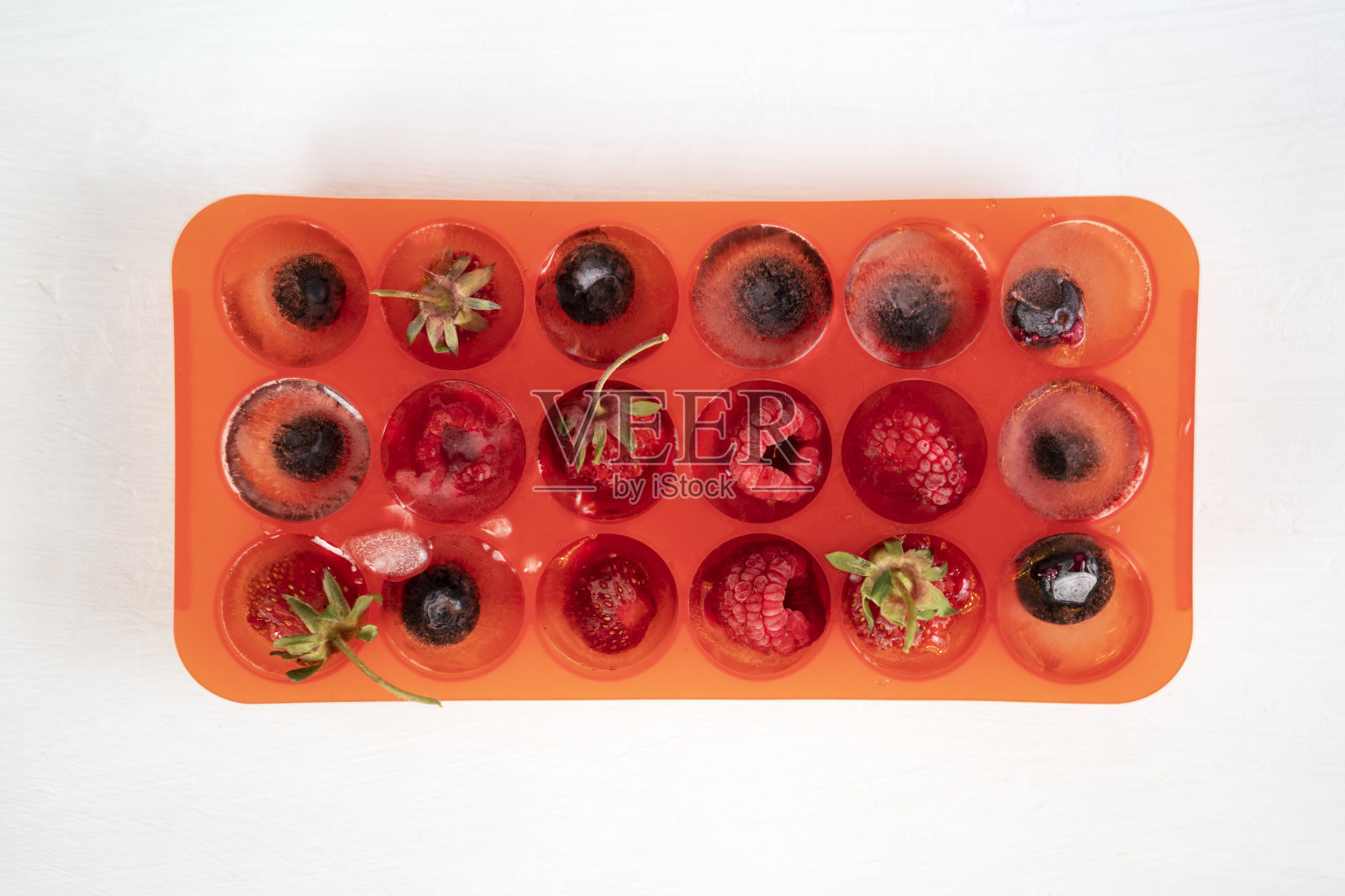 冰冻浆果在红色硅胶托盘或模具冰块。俯视图照片摄影图片