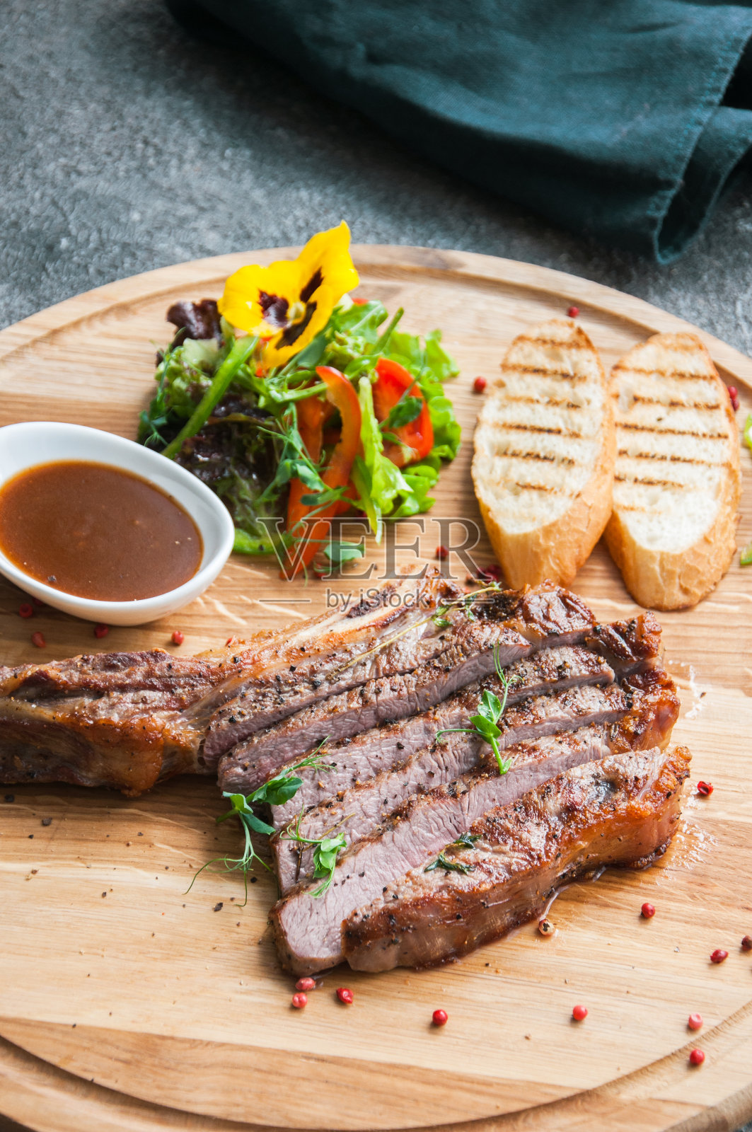 在灰色背景的木板上烤牛排。前视图。照片摄影图片