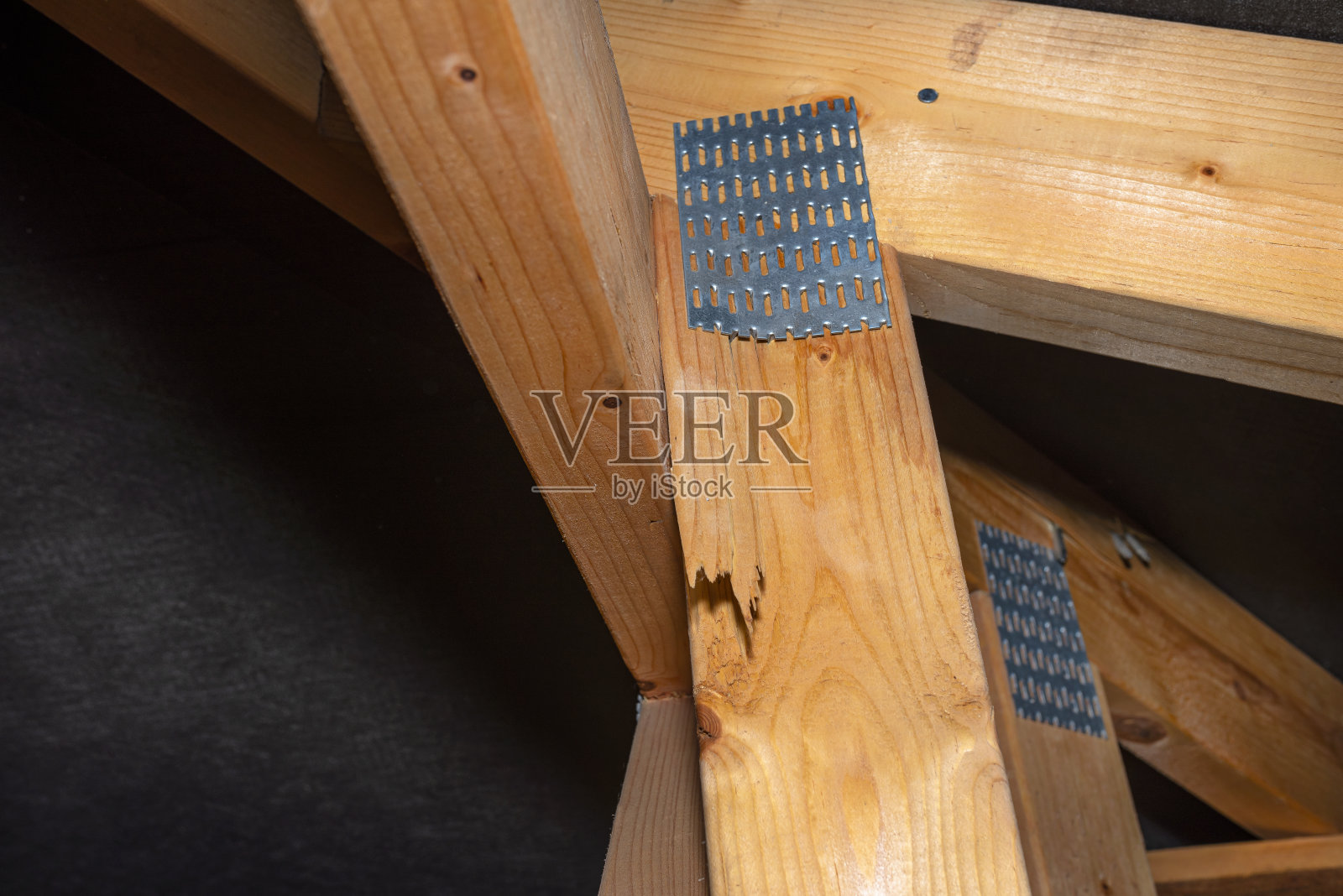 受损的倒刺板连接着覆盖着薄膜的独栋房屋的屋顶结构,可见受损的桁架。照片摄影图片