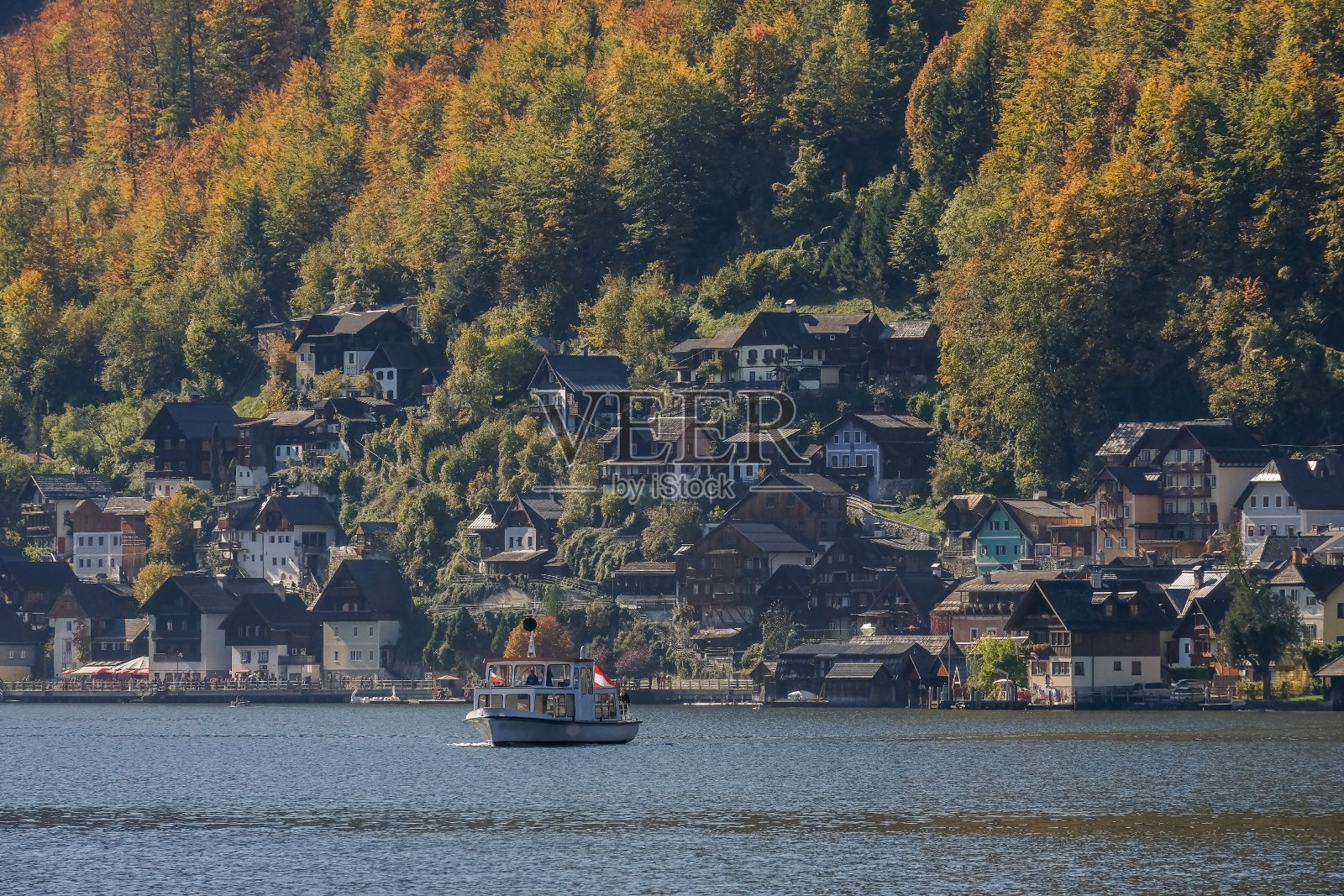 奥地利阿尔卑斯山脉上的哈尔斯塔特湖覆盖着一吨树木和树叶,从绿色到红色的镜头在秋天的蓝天上照片摄影图片
