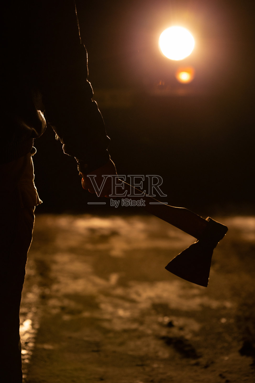 一个人夜里站在路上,手里拿着一把斧头照片摄影图片