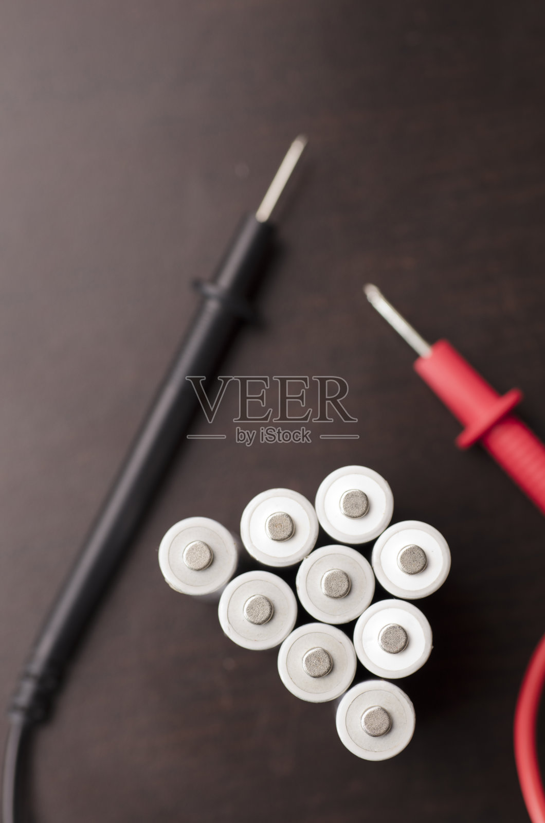 一组电池与电压表,红色正极,黑色负极,在工作台上照片摄影图片
