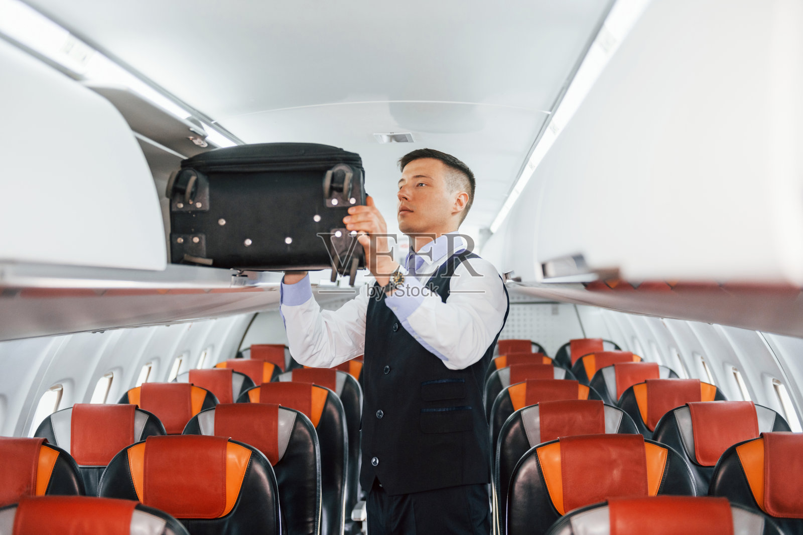 穿着制服的年轻乘务员在客机上工作照片摄影图片