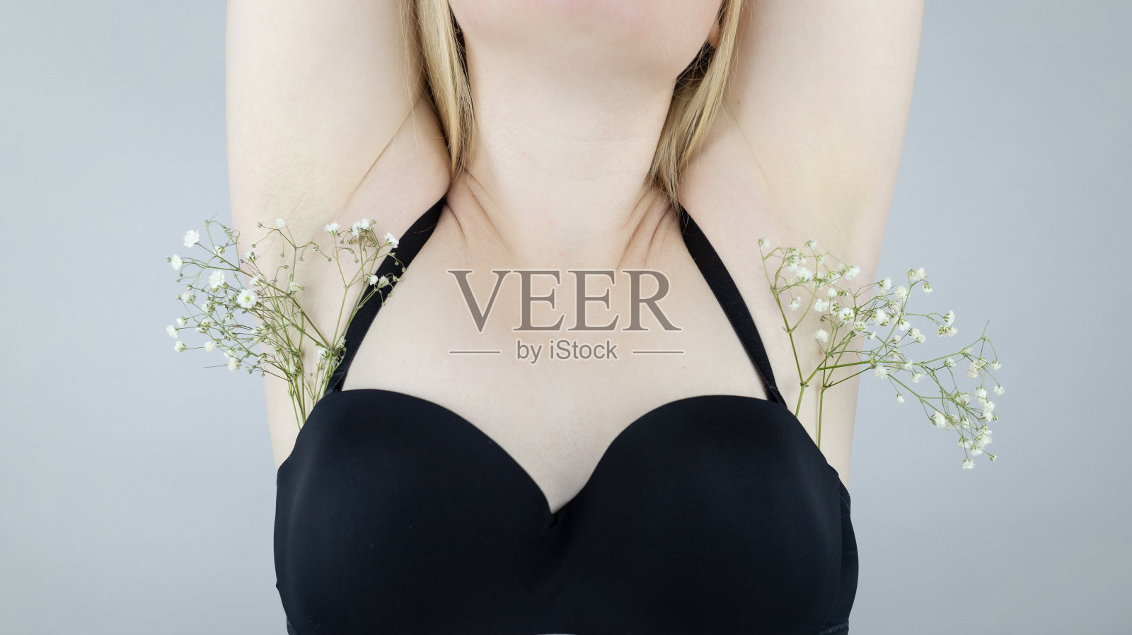 女人的腋下插着花,象征着长了头发。概念图。身体的积极性和接受度。用剃须刀或激光去除毛发。个人护理。照片摄影图片