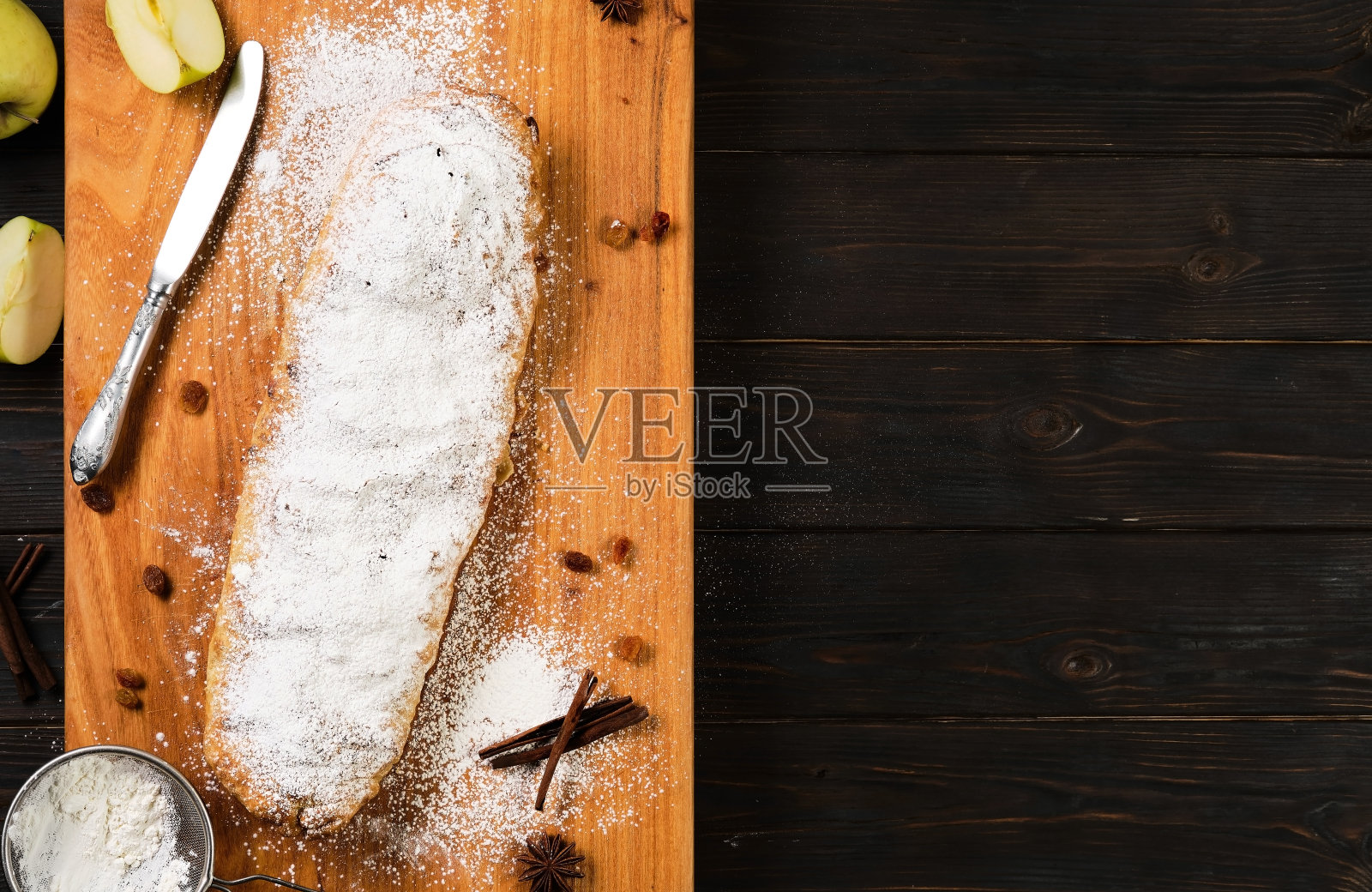 苹果派-苹果馅饼,是奥地利的一种烘焙甜点,里面有焦糖苹果、坚果、肉桂和葡萄干,放在木切板上,配以茴芹和肉桂棒。顶部视图与复制空间照片摄影图片