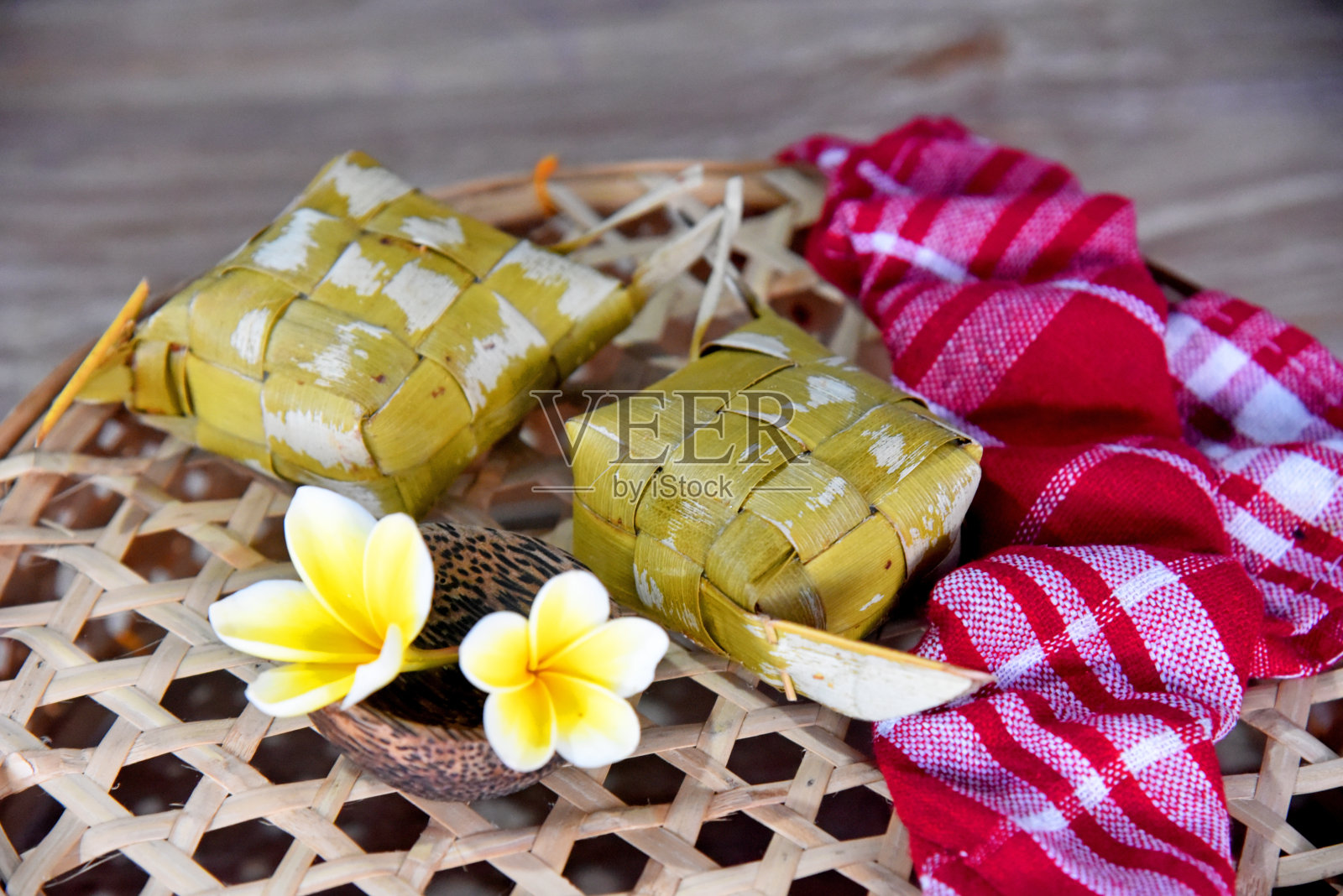印尼传统食物名为“Ketupat”,放在竹篮上,用红色的餐巾和鸡蛋花装饰照片摄影图片