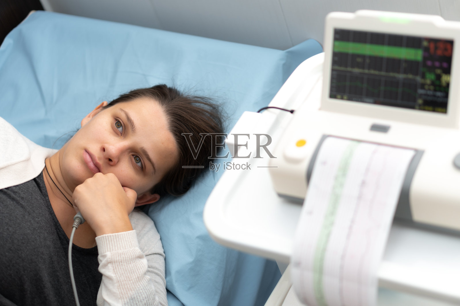 在医疗控制心脏造影期间,疲惫的孕妇躺在医院沙发上。妇科医生就诊孕期顾问。检查孕妇腹部健康检查照片摄影图片