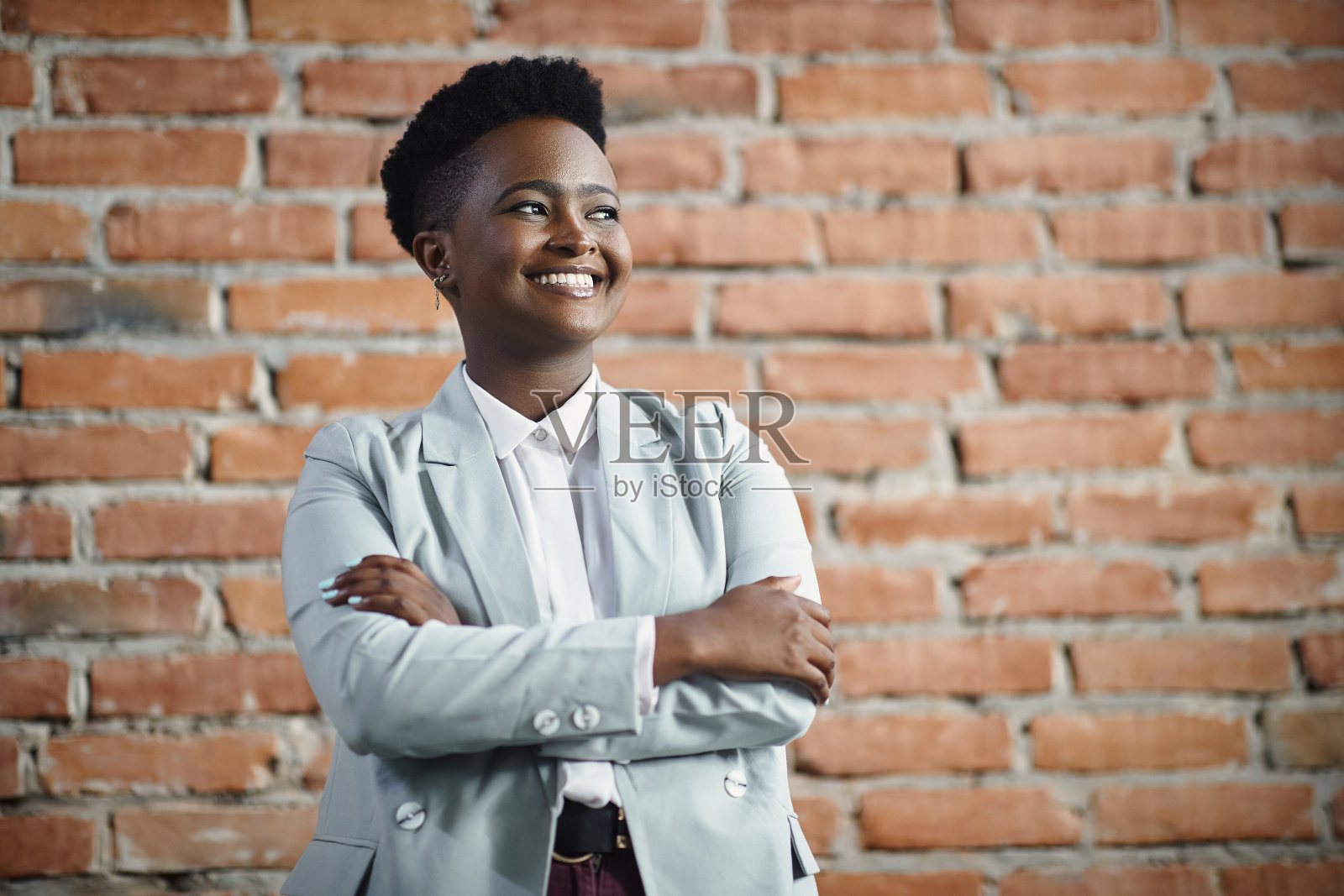 自信的黑人CEO双臂交叉站着,望向别处。照片摄影图片