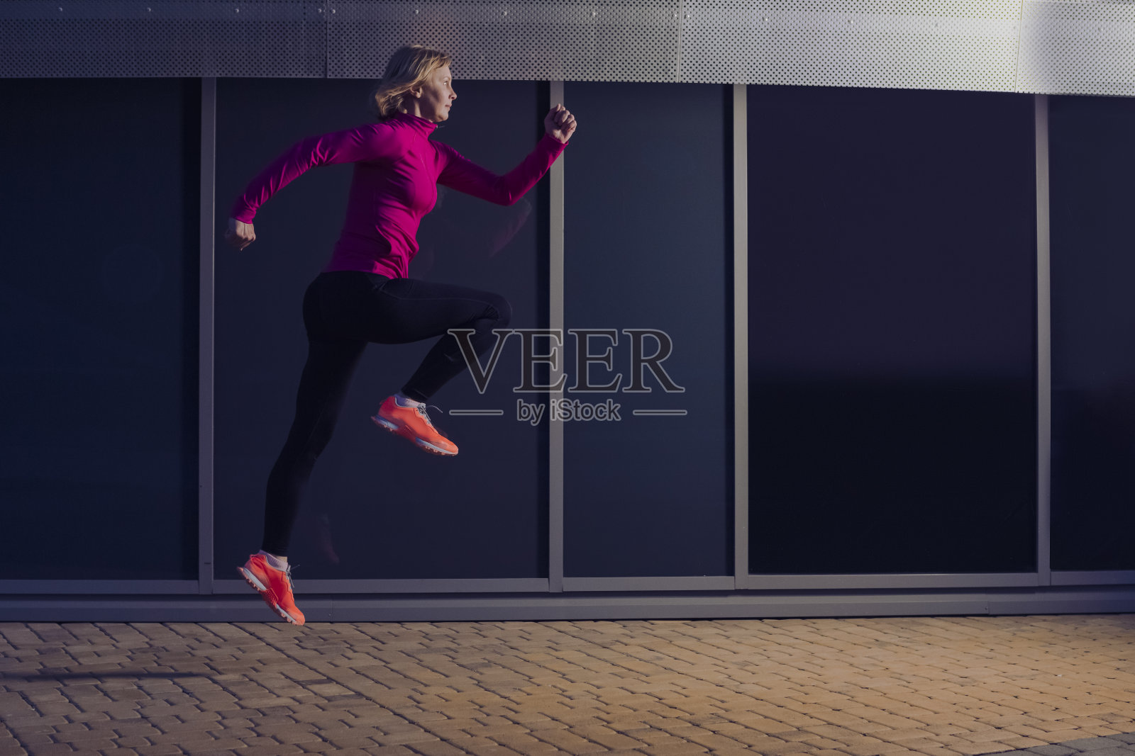 专业的成熟的高级跑步者,户外慢跑训练的反光玻璃表面的背景。照片摄影图片