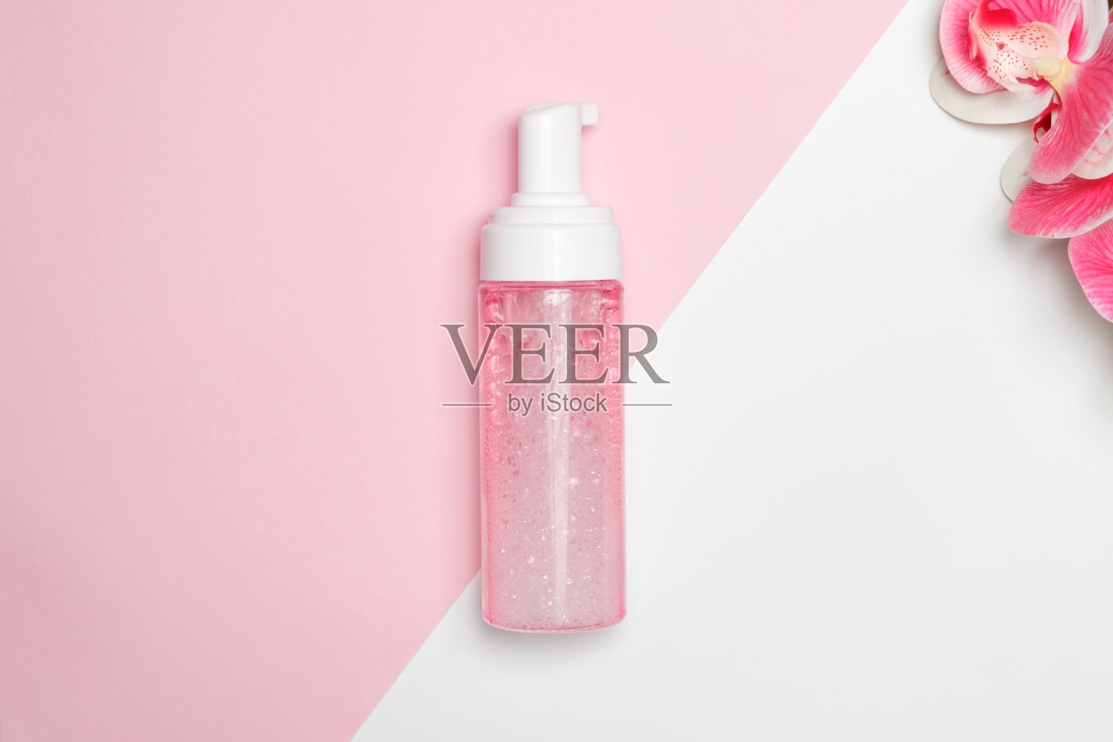 泡沫装在塑料瓶里,背景是兰花。照片摄影图片