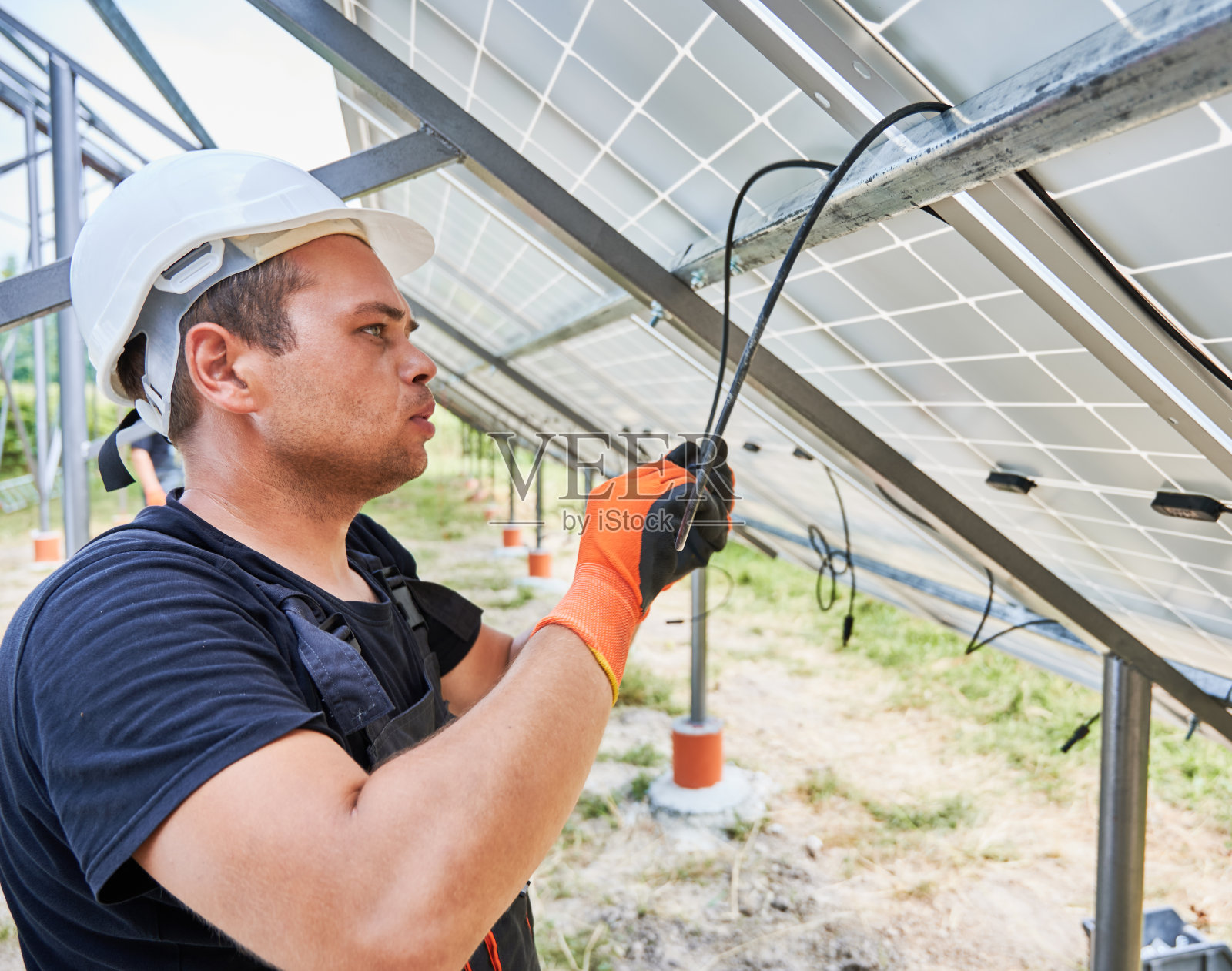 工人用绳索将太阳能电池板固定在金属横梁上照片摄影图片