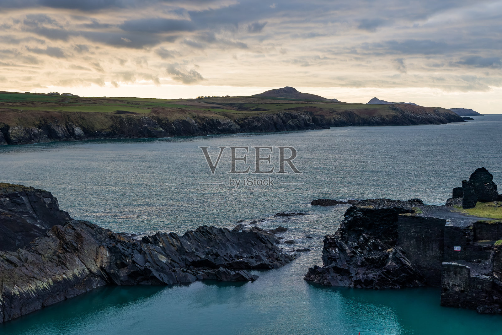 在威尔士彭布罗克郡阿伯雷雷迪附近的蓝礁湖,戏剧性的海岸线和阴沉的日落天空照片摄影图片